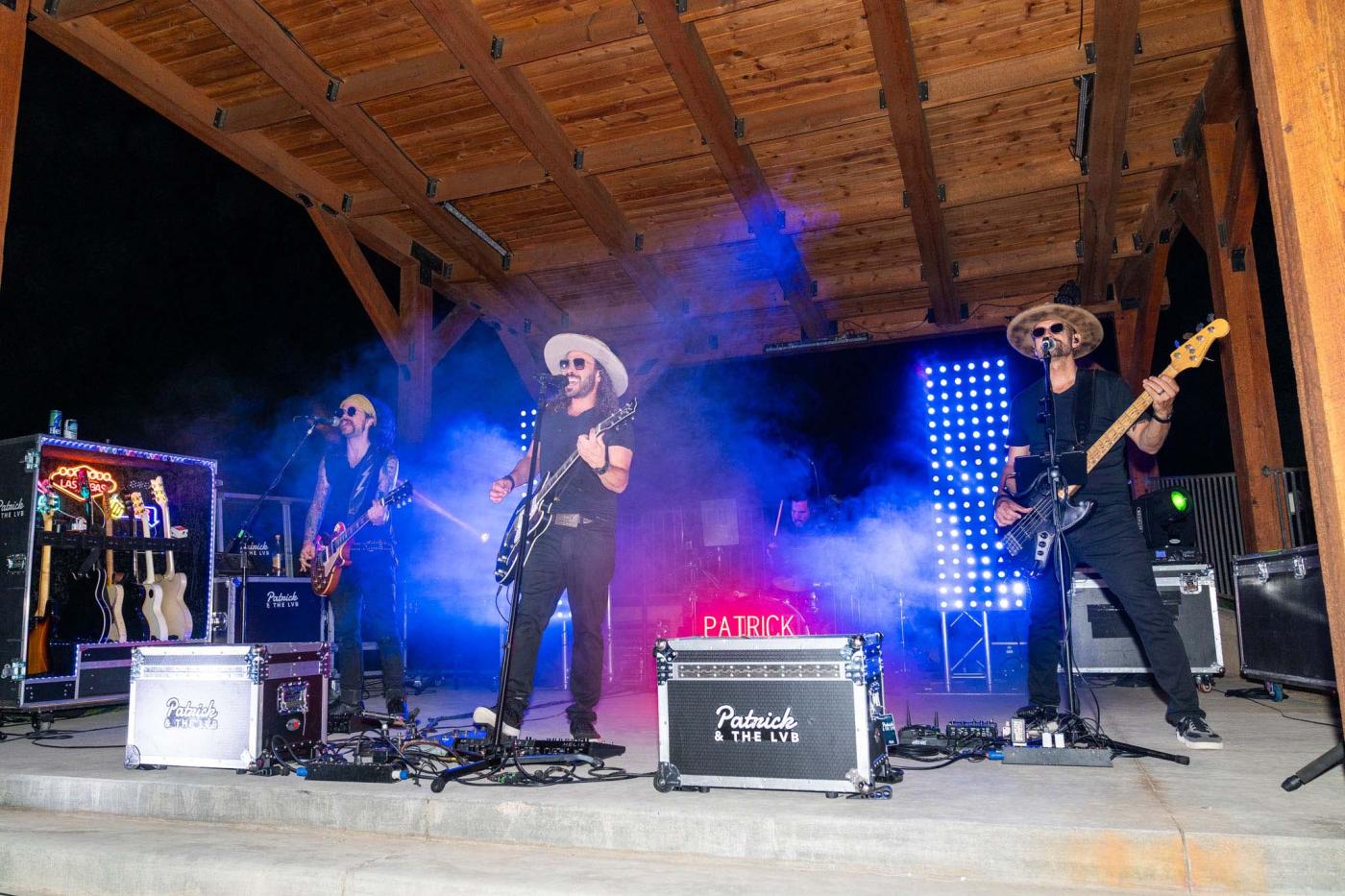 Three musicians on stage with bright lights and smoke